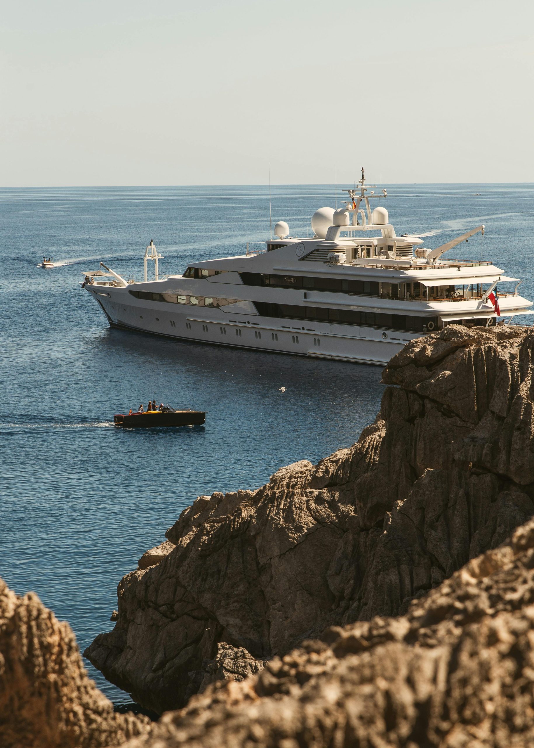 A luxury yacht cruising near rocky cliffs on a sunny day in Spain, showcasing adventure and travel.